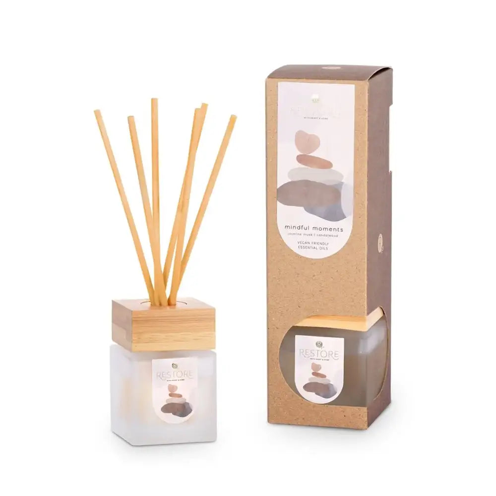 A reed diffuser with wooden sticks and packaging on a white background