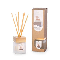 A reed diffuser with wooden sticks and packaging on a white background