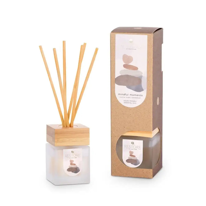 A reed diffuser with wooden sticks and packaging on a white background