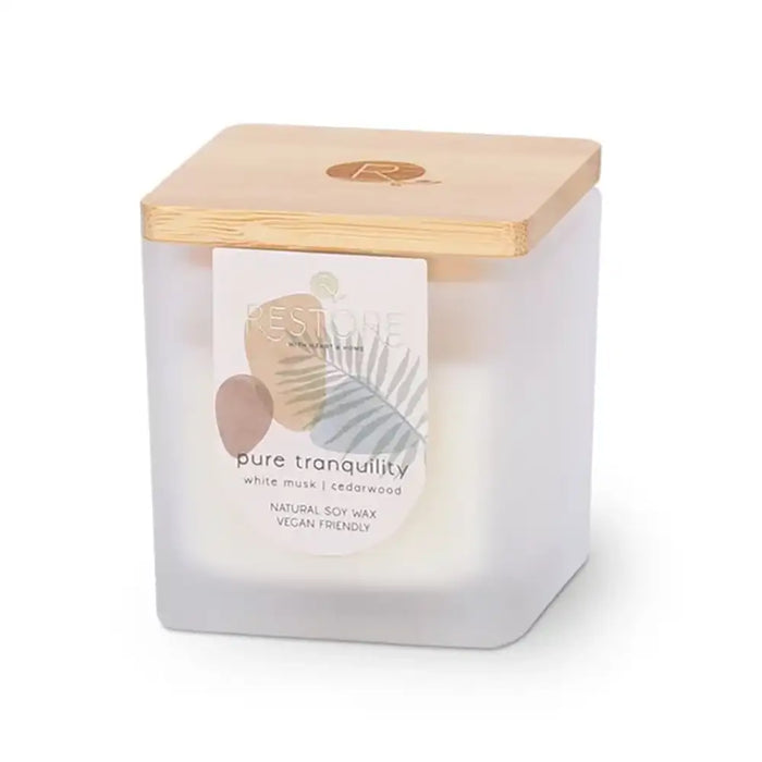 Candle in a white container with a wooden lid on a white background