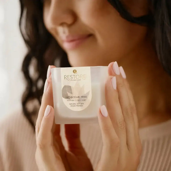 Woman holding a skincare product labeled 'RESTORE' with a blurred background