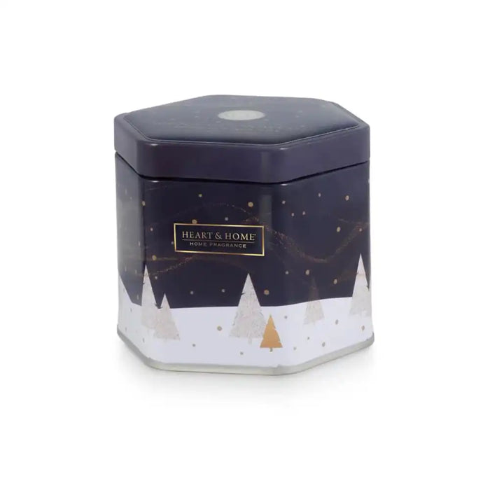 A hexagonal metal tin candle from Heart & Home Candle Co., featuring a dark navy blue top half with gold stars and a white bottom half with gold and silver pine trees, shown on a white background.