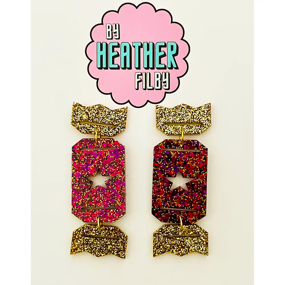 Pair of colorful earrings with gold accents on a white background, branded by Heather Filby.