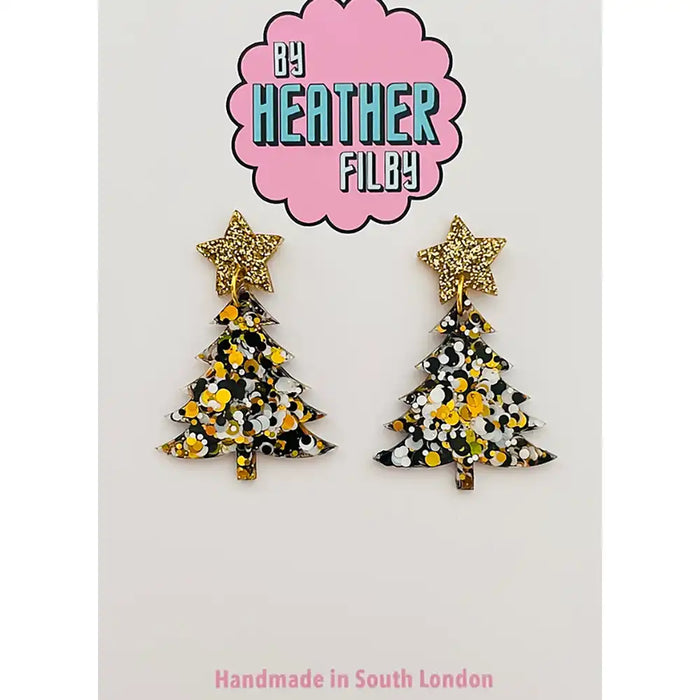 Pair of star-shaped earrings with Christmas tree design on a white background, branded by Heather Filby.