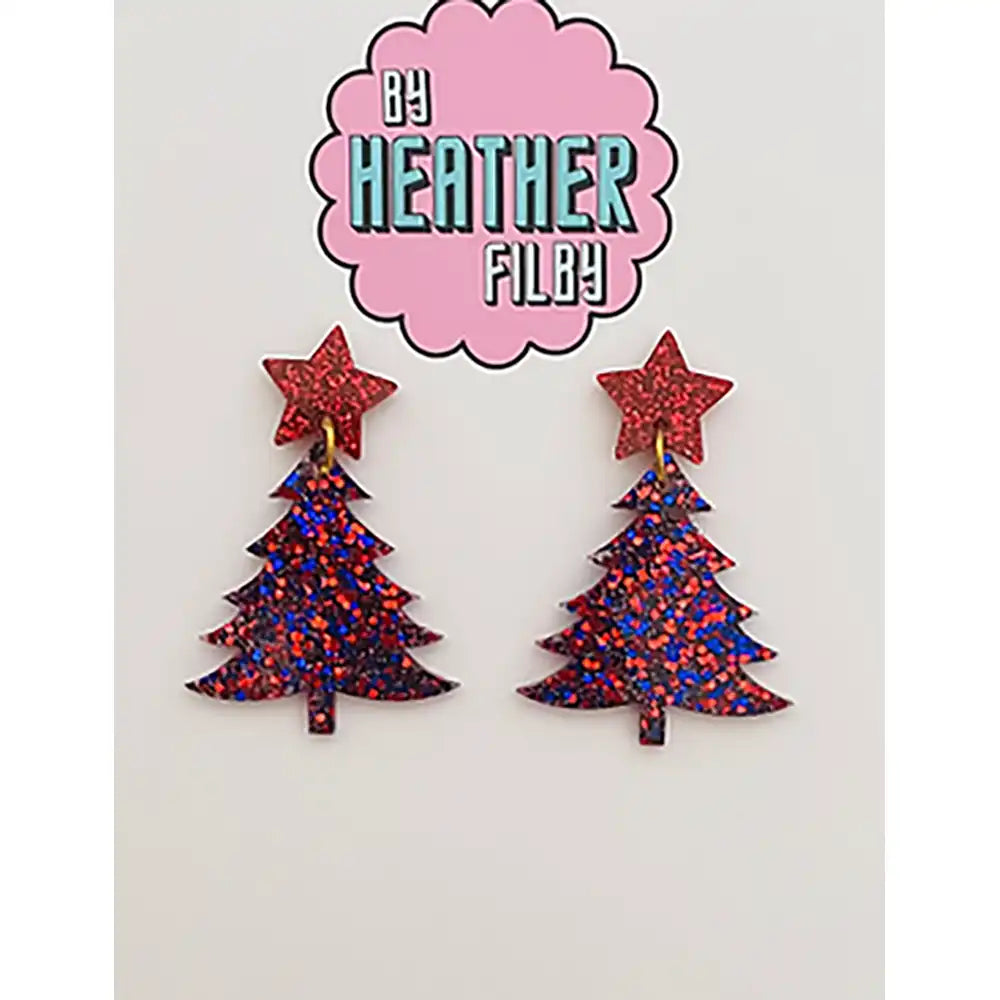 Glittery Christmas tree earrings with a pink label reading 'By Heather Filby' on a white background.