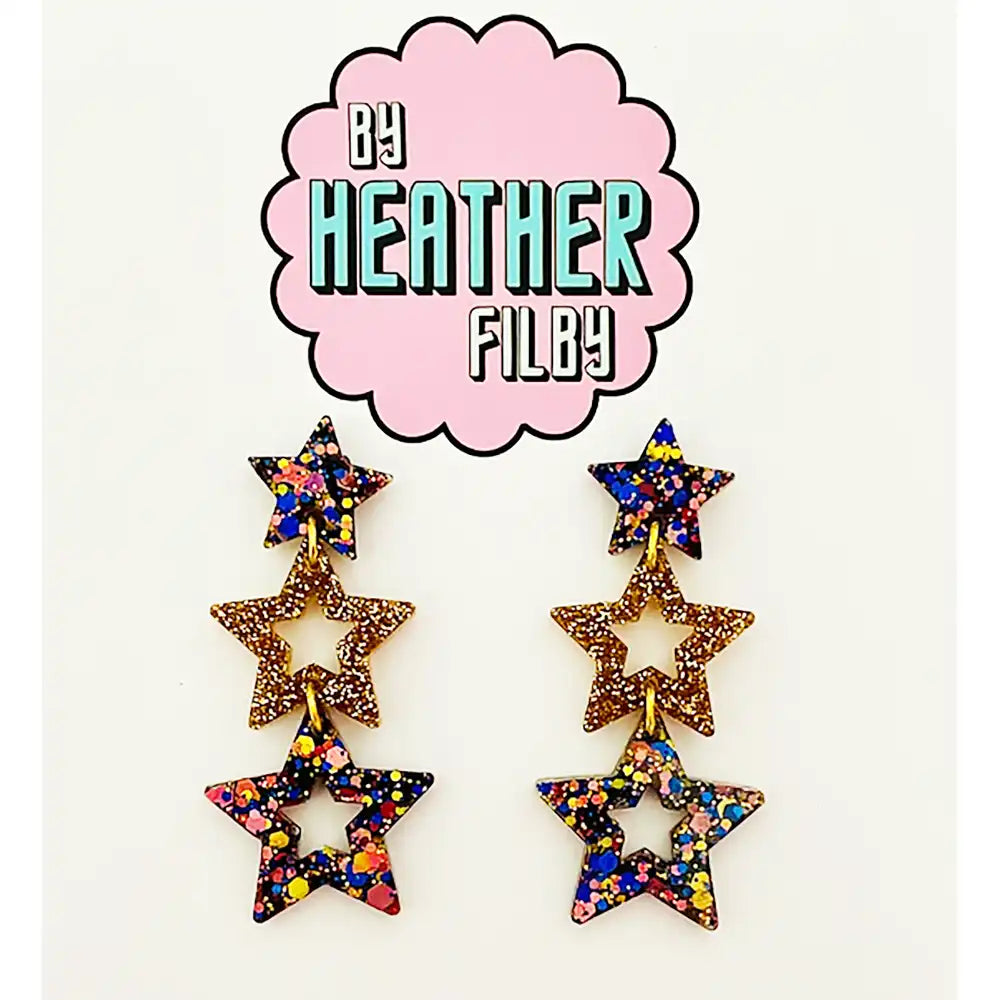 Star-shaped earrings with multicolor glitter on a white background with 'By Heather Filby' logo.