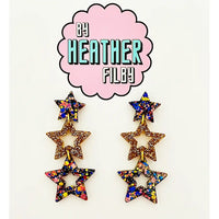Star-shaped earrings with multicolor glitter on a white background with 'By Heather Filby' logo.