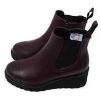 A side view of a pair of plum ankle boots with a visible brand label on a white background. Shows low wedge.