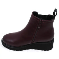 Single plum ankle boot with a black  wedge sole on a white background showing the full side zip.