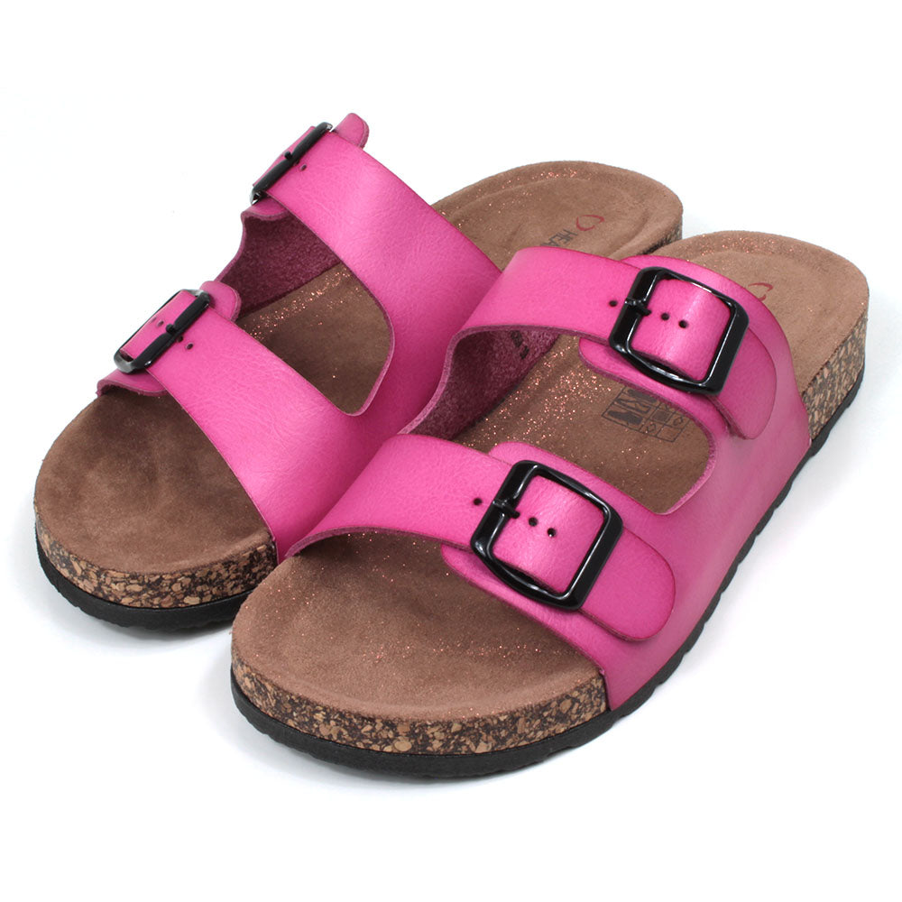 Pink double strap fuchsia pink sandals from Heavenly Feet. Backless, adjustment is with two black buckles. Cork effect sculpted footbeds with pink glitter sprinkled along the floor. Angled view.