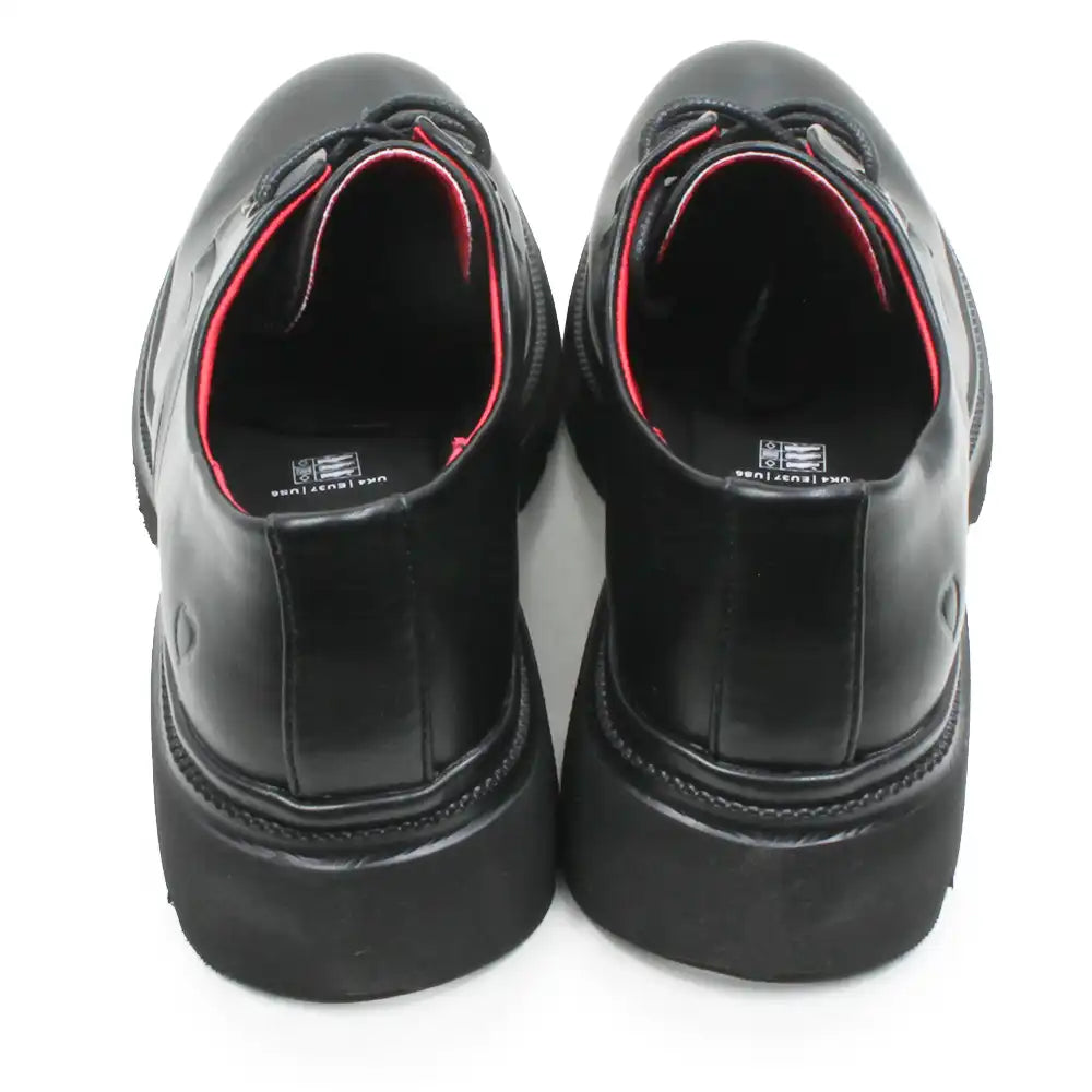 A pair of black leather lace-up shoes with chunky black platform soles, shown from a rear three-quarter view on a white background.