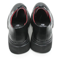 A pair of black leather lace-up shoes with chunky black platform soles, shown from a rear three-quarter view on a white background.
