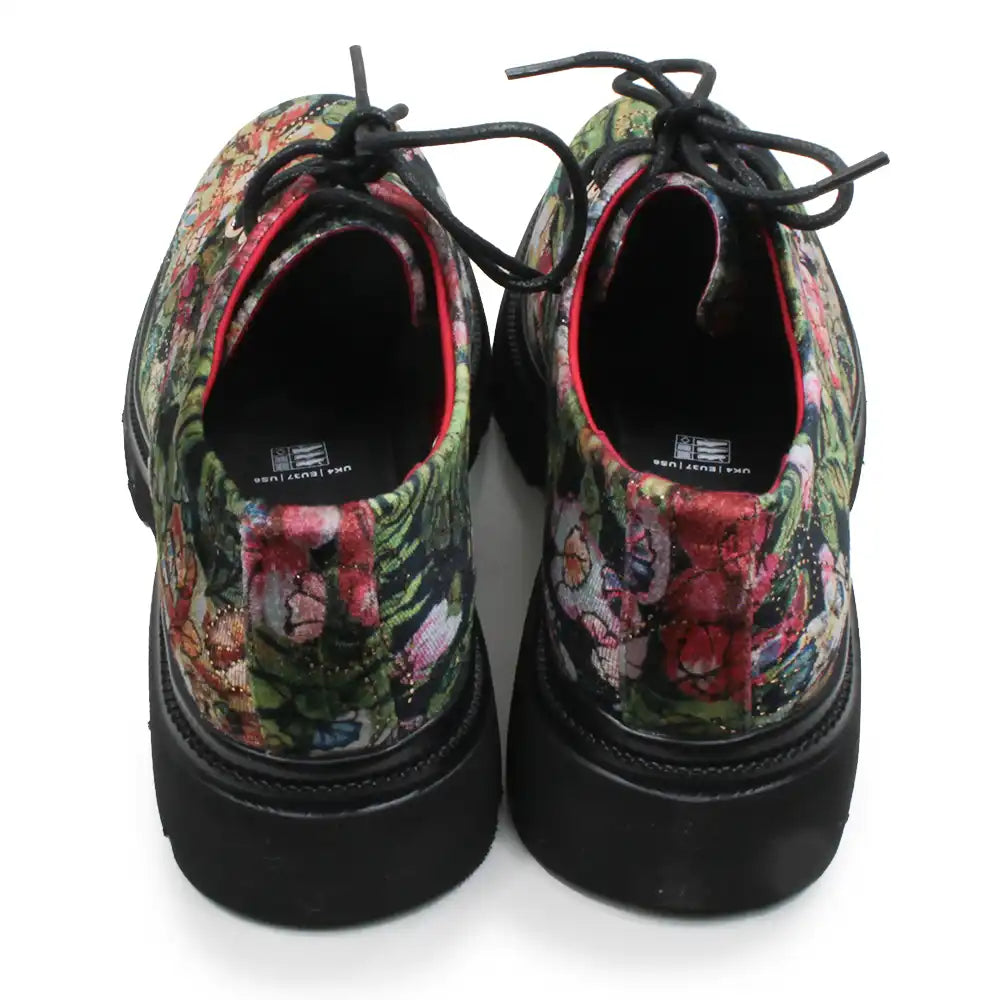 A pair of lace-up shoes shown from the back, featuring a vibrant, multicolored floral and abstract print on the uppers with solid black soles and black laces.