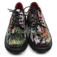 A pair of lace-up oxford-style shoes with thick black soles and black laces, featuring a vibrant, multicolored floral and abstract print on the uppers. The interior lining is red, and the shoes are photographed against a plain white background.