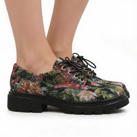 A pair of women's lace-up oxford-style shoes with a dense multicolor floral print and chunky black platform soles, shown on a model's feet against a white background.