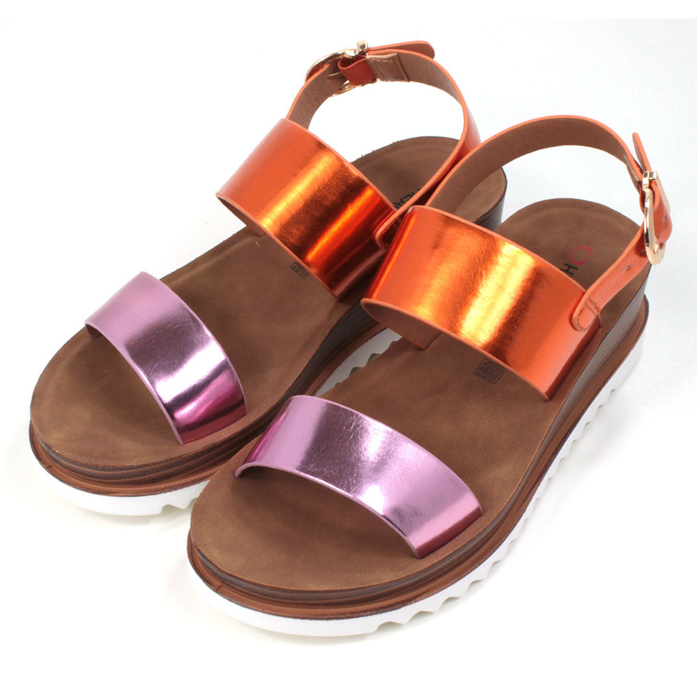 Pink and orange metallic effect sandals with buckled ankle strap. Two wide over the foot straps. Tan coloured footbed. White rubber soles. Angled view