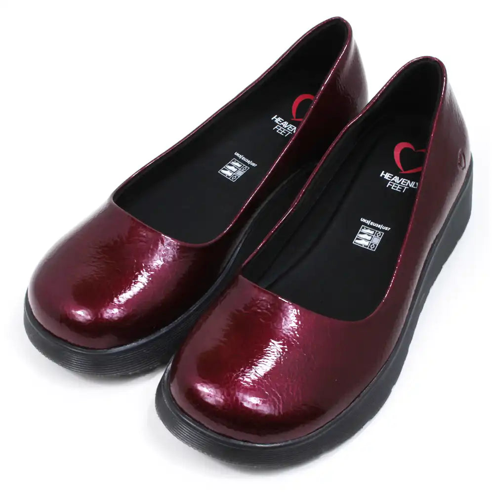 Pair of patent maroon slip on shoes with black low wedge soles. Round toes. Angled view.