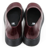 Pair of patent maroon slip on shoes with black low wedge soles. Round toes. Back view.