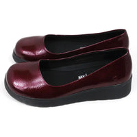 Pair of patent maroon slip on shoes with black low wedge soles. Round toes. Side view.