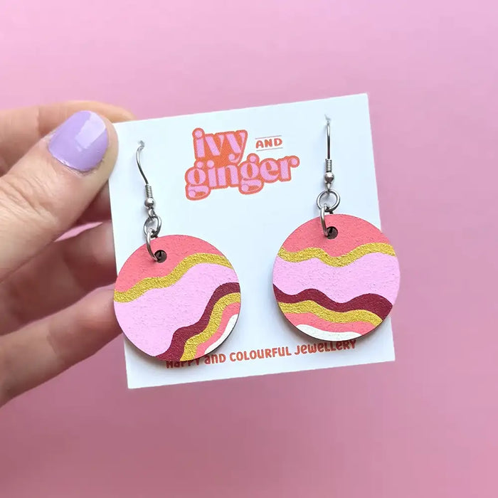 Pink and yellow wavy patterned earrings on a 'Ivy and Ginger' branded card against a pink background.