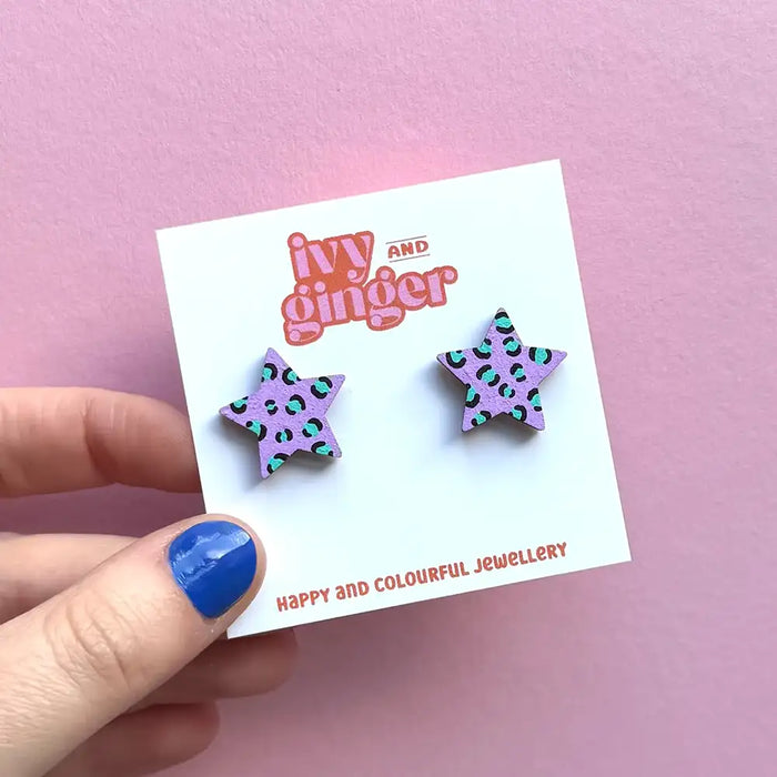 Star-shaped earrings on a 'ivy and ginger' branded card against a pink background