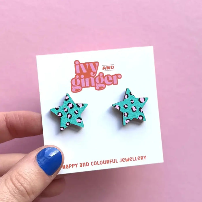 Turquoise star-shaped earrings on a 'ivy and ginger' branded card against a pink background.