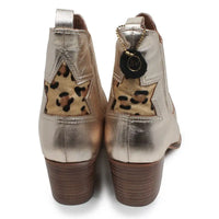 A pair of metallic gold ankle boots shown from the back, featuring a leopard-print star detail on the back of the heel and a dark brown stacked block heel.