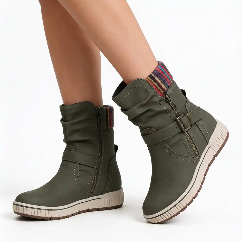 A pair of women's olive green ankle boots with side zippers, buckle straps, and a multicolor knit collar, shown on a model's feet against a white background.