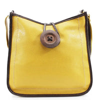 A yellow pebbled leather shoulder bag with dark brown trim, featuring a large round brown button closure on the front and a thin shoulder strap.