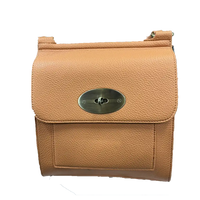 A tan pebbled leather shoulder bag with a silver-tone oval turn-lock closure on the front flap, shown against a plain white background.
