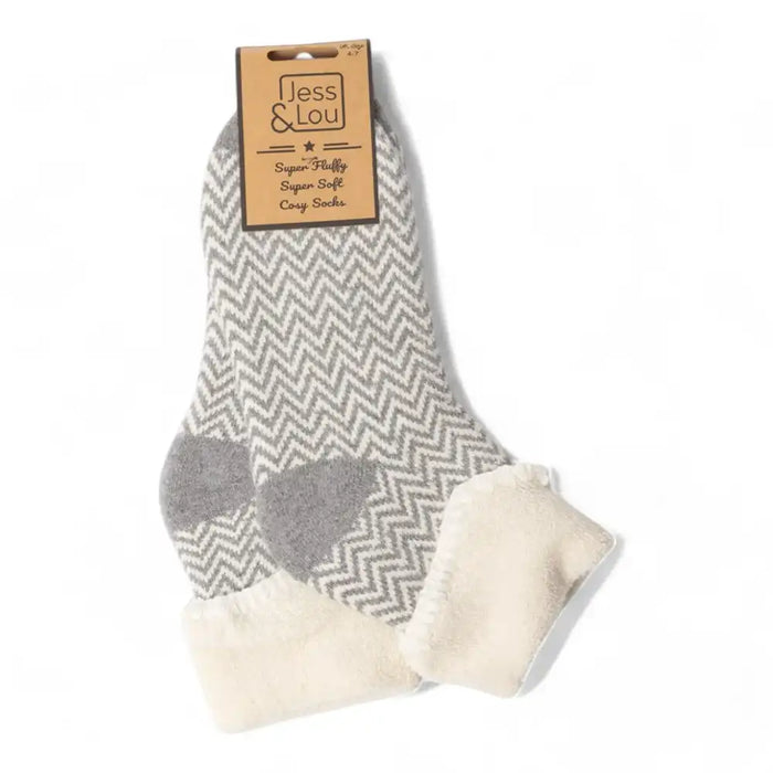 A pair of gray and white chevron-patterned socks with a soft cream fleece cuff and heel, packaged with a brown paper header card that reads 'Jess & Lou'.