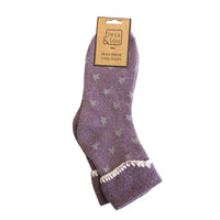 A pair of purple wool blend cozy socks with a light grey star pattern and white tassel trim, shown on a white background with a cardboard hanger.