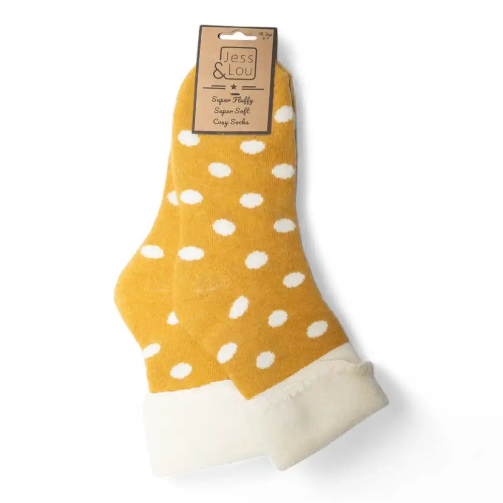 A pair of yellow ankle socks with white polka dots and white fleece cuffs, packaged with a brown paper header card on a white background.