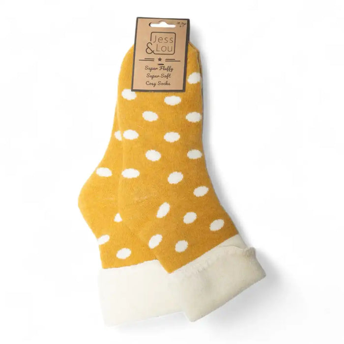 A pair of yellow ankle socks with white polka dots and white fleece cuffs, packaged with a brown paper header card on a white background.