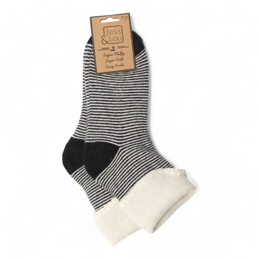 A pair of Jess & Lou socks with black and white stripes, solid black heels and toes, and a soft cream fleece lining at the cuffs, shown with their cardboard header packaging on a white background.