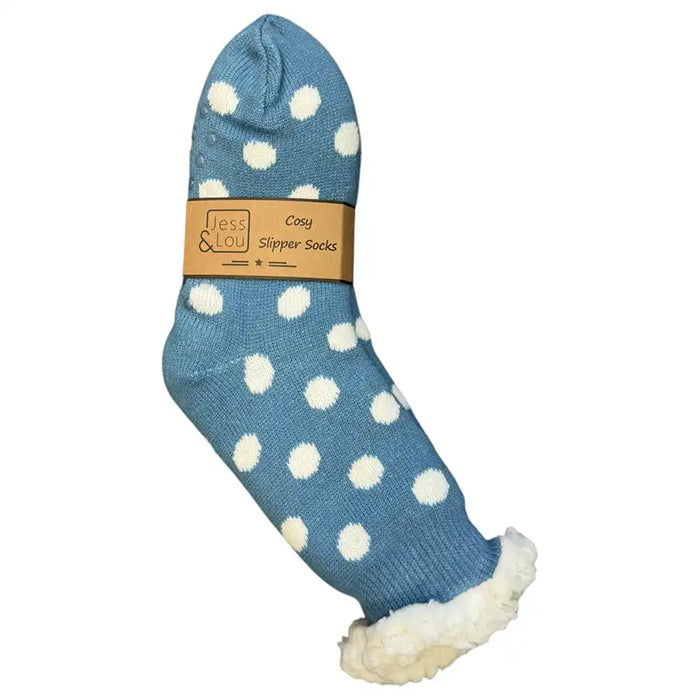 A single blue slipper sock with white polka dots and a white sherpa lining, shown on a plain white background with a paper band label.
