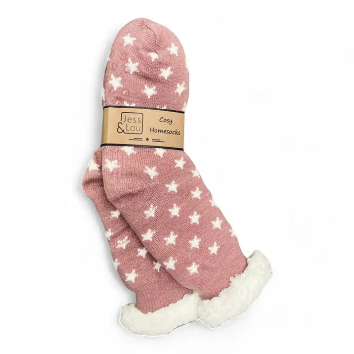 A pair of pink knit home socks with white star patterns and a white sherpa lining, wrapped in a tan paper band that reads 'Jess & Lou Cozy Homesocks'.