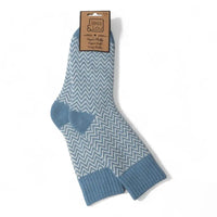 A pair of blue and white chevron-patterned crew socks with solid blue ribbed cuffs and heels, hanging from a brown paper tag that reads 'Jess & Lou'.