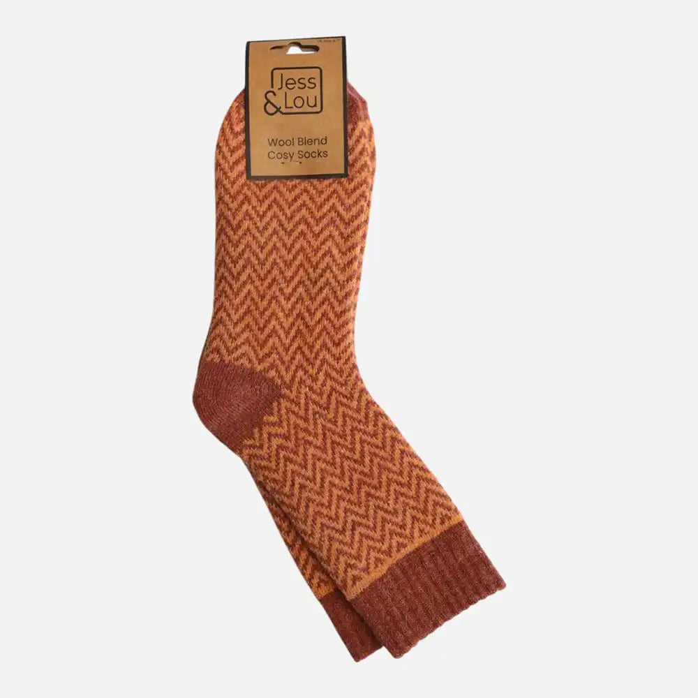 A pair of orange and brown patterned crew socks with a cardboard hanger tag, displayed against a light gray background.