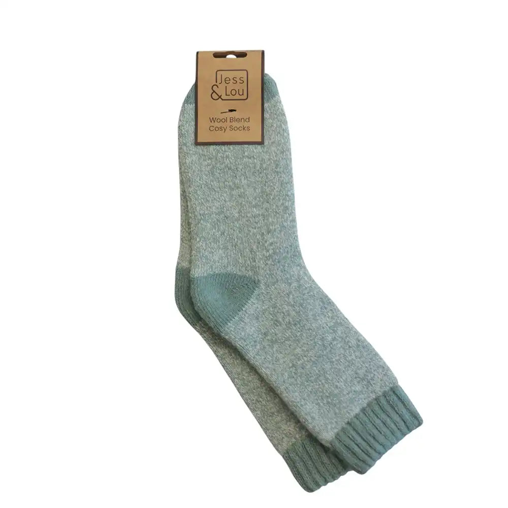 A pair of light blue-green wool blend crew socks with a matching ribbed toe and heel, hanging from a brown paper tag that reads 'Jess Lou Wood Blend Coy Socks' on a solid white background.