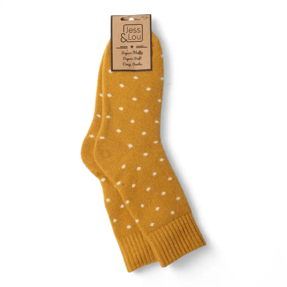 A pair of mustard yellow crew socks with small white polka dots, hanging from a paper tag that reads 'Jess & Lou'.
