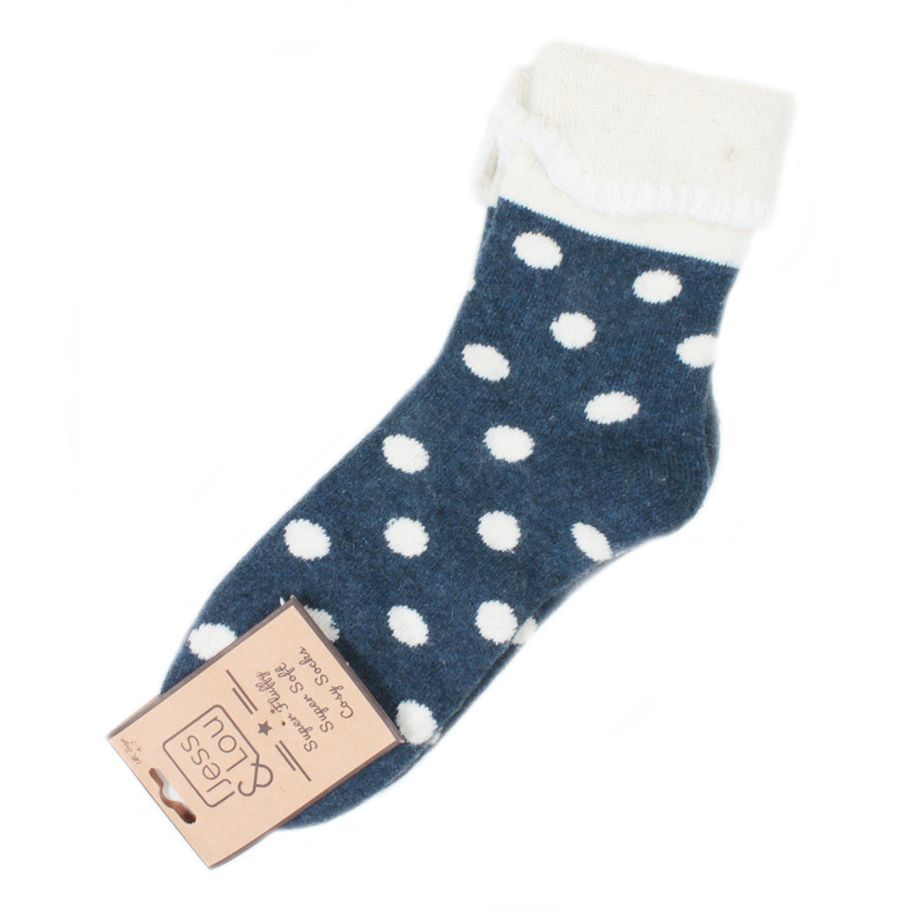 A single navy blue knit sock with white polka dots and a white fuzzy cuff, shown with a paper hangtag on a plain white background.