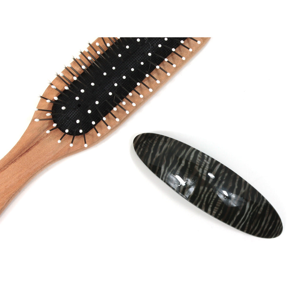 Grey animal pattern plastic elongated hair clip. Hairbrush pictured for size illustration.
