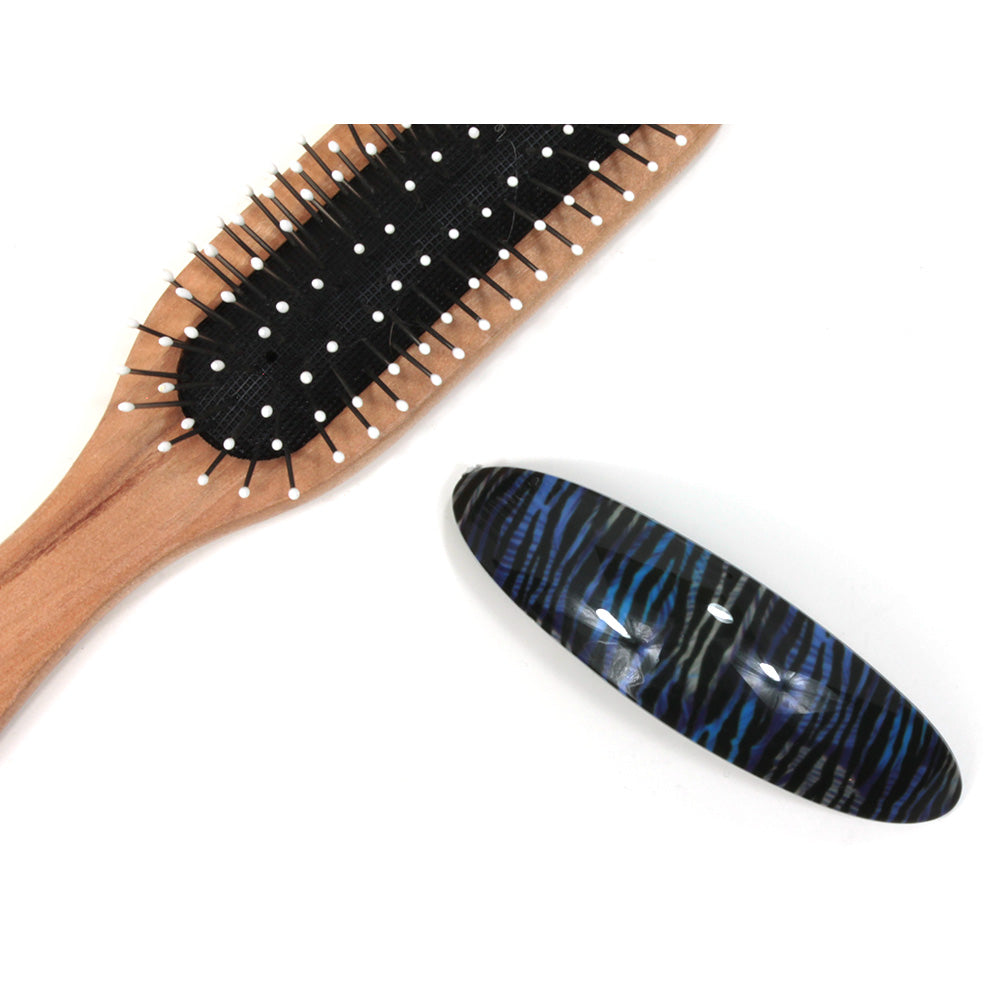 Blue and grey animal pattern plastic elongated hair clip. Hairbrush pictured for size illustration.