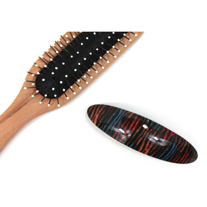 Blue and orange animal pattern plastic elongated hair clip. Hairbrush pictured for size illustration.