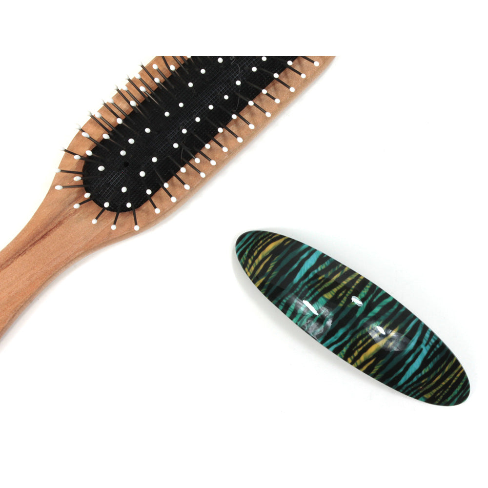 Teal and yellow animal pattern plastic elongated hair clip. Hairbrush pictured for size illustration.