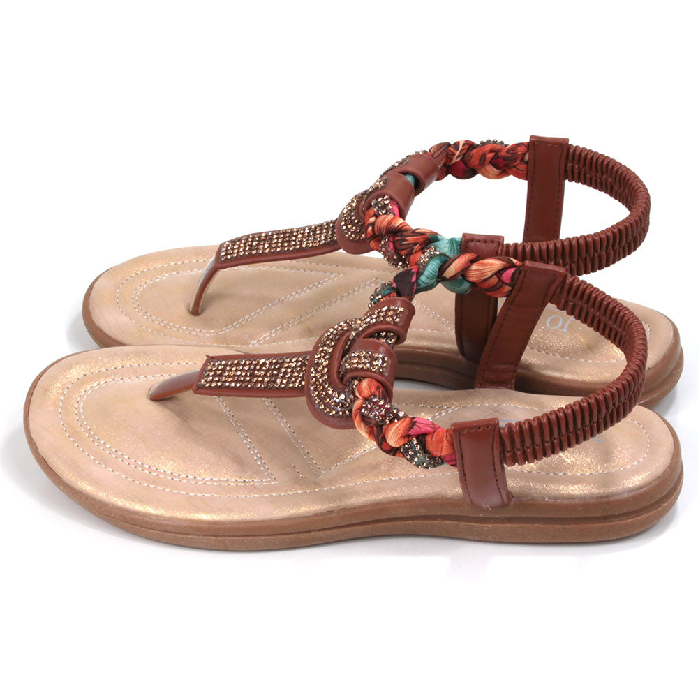 Tan coloured toe post sandals with elasticated back. Jewels and fabric decoration. Light tan coloured insoles. Side view.
