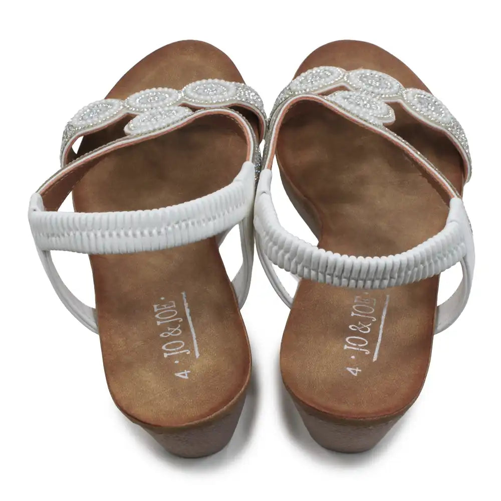 Pair of white sandals with decorative straps on a white background