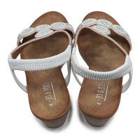 Pair of white sandals with decorative straps on a white background