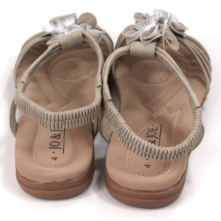 Suede look, light tan sandals with over toes straps and elasticated straps around the ankles. Suede look floral corsages over the feet. Tan coloured padded insoles. Back view.